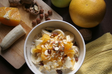 Still-life of a Bircher Muesli with fresh fruits and hazelnuts in a morning light atmosphere taken on a kitchen table.