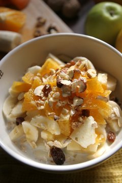 Still-life of a Bircher Muesli with fresh fruits, honey and hazelnuts in a morning light atmosphere taken on a kitchen table, close-up