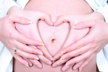 Future parents hold on the child, hands in the form of heart