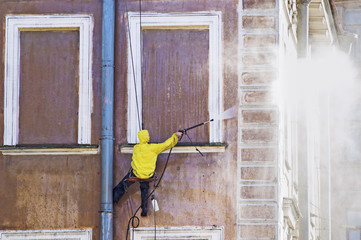 Cleaning service worker washing old building facade