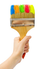 woman's hand holding big brush with different colors of paint