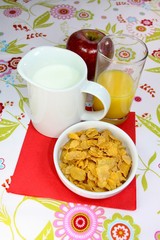 Orangensaft, Cornflakes, Milch und Apfel zum Frühstück