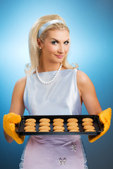 Beautiful woman holding hot roasting pan with oat cookies on it.