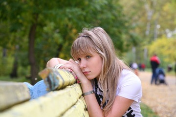 single girl on a bench in an autumn park