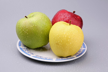 Three tasty multi-coloured apples on a plate