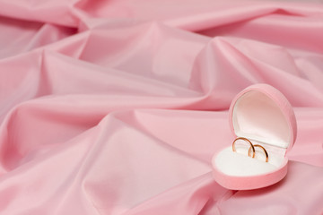 Wedding rings on background of the pink silk.