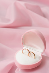 Wedding rings on background of the pink silk.