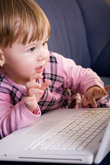 Fototapeta na wymiar Beutiful little girl play with white laptop computer