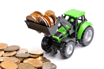 Green tractor raking up coins