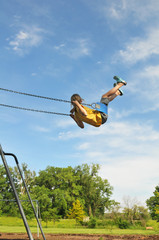 Young girl on swing against a blue sky