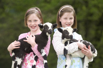Twin girls with lambs
