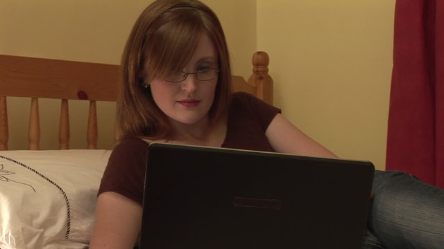 Woman working on a laptop on bed