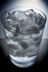 Glass full of ice and water on blue background