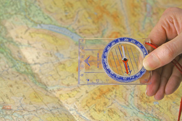 hand holding compass over map