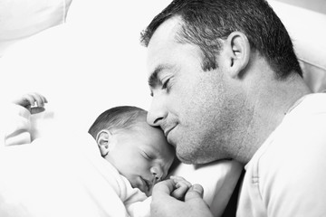 black and white close-up of father holding his newborn baby