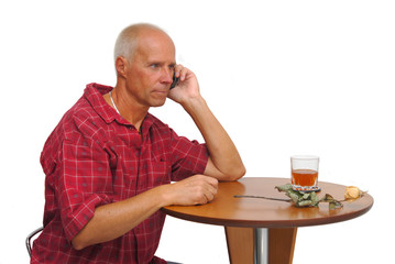 Mature man at the phone with a dry rose on the table