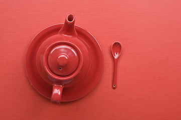 Teapot and spoon on red table