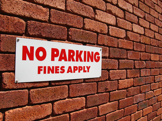 No Parking sign on a red brick wall