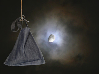 Moon on a dark sky with a bag  hanging in the foreground