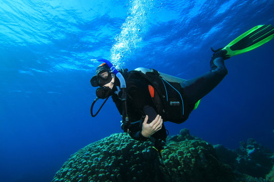 Woman Scuba Diver swims over Coral Reef