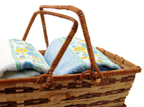 Two rolled up towels with flower decoration in wicker basket