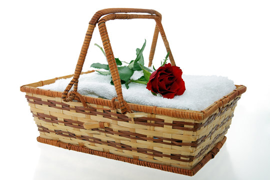 White towels in wicker basket with red rose
