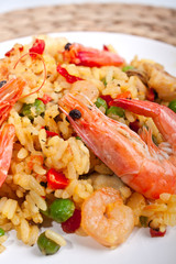 serving of Spanish paella on s white plate with king shrimps