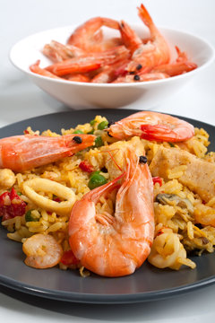 Spanish paella on a dark plate with king shrimps