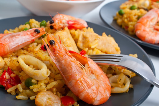 Spanish paella on a dark plate with king shrimps