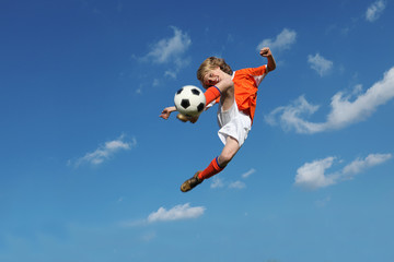 child playing football or soccer kicking ball