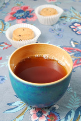 Teeschale mit Gebäck auf bunter Tischdecke