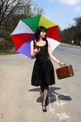 girl with vintage suitcase and umbrella outdoors