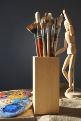 Art brushes in a wooden glass with a palette and model