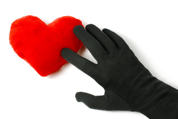Rotes Plüschherz berührt von der Hand im schwarzen Handschuh