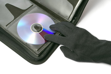 Hand im schwarzen Handschuh greift nach einer CD/DVD