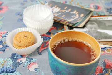 Teeschale mit Gebäck und Fotos auf bunter Tischdecke