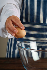 Woman chef breaking egg into bowl