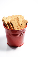 Closeup of brown dog treats in a red bucket.