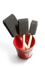 Shiny red bucket contains three foam paint brushes.