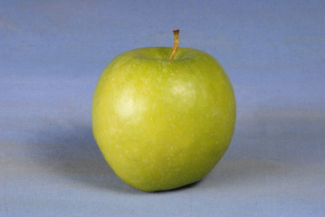 Green apple on light blue background.