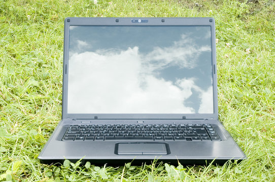 laptop on grass with sky reflection