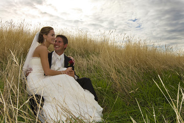 happy wedding couple sitting in grass