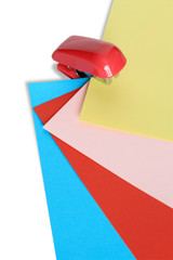 Red stapler with color papery sheets isolated on white
