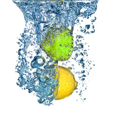 lemon and lime dropped into water with bubbles isolated on white