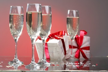 Glasses of champagne, gifts with red tapes and bows