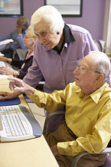 Senior woman helping senior man use computer