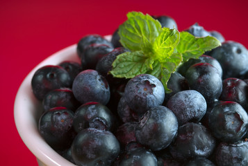 Blueberries in bowl on red background