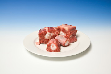 Plate of Ox tail meat on a graduated blue studio background.