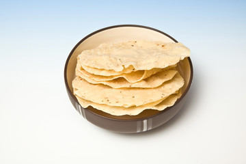 bowl of Pappadums on a blue studio background.