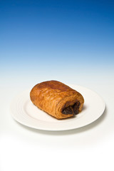 Chocolate croissaint on a blue studio background.